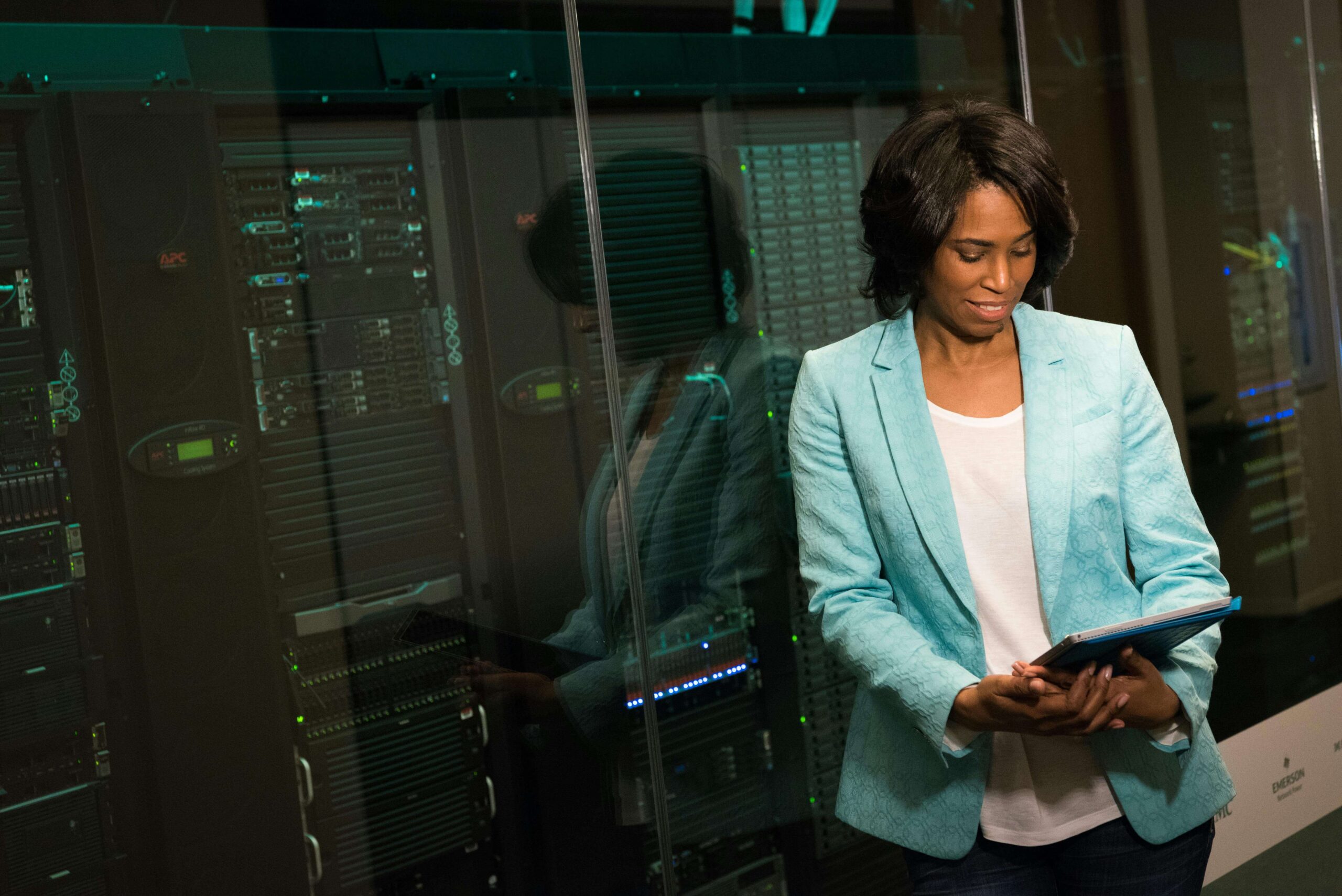 woman in a blazer holding a tablet while standing next to servers 
