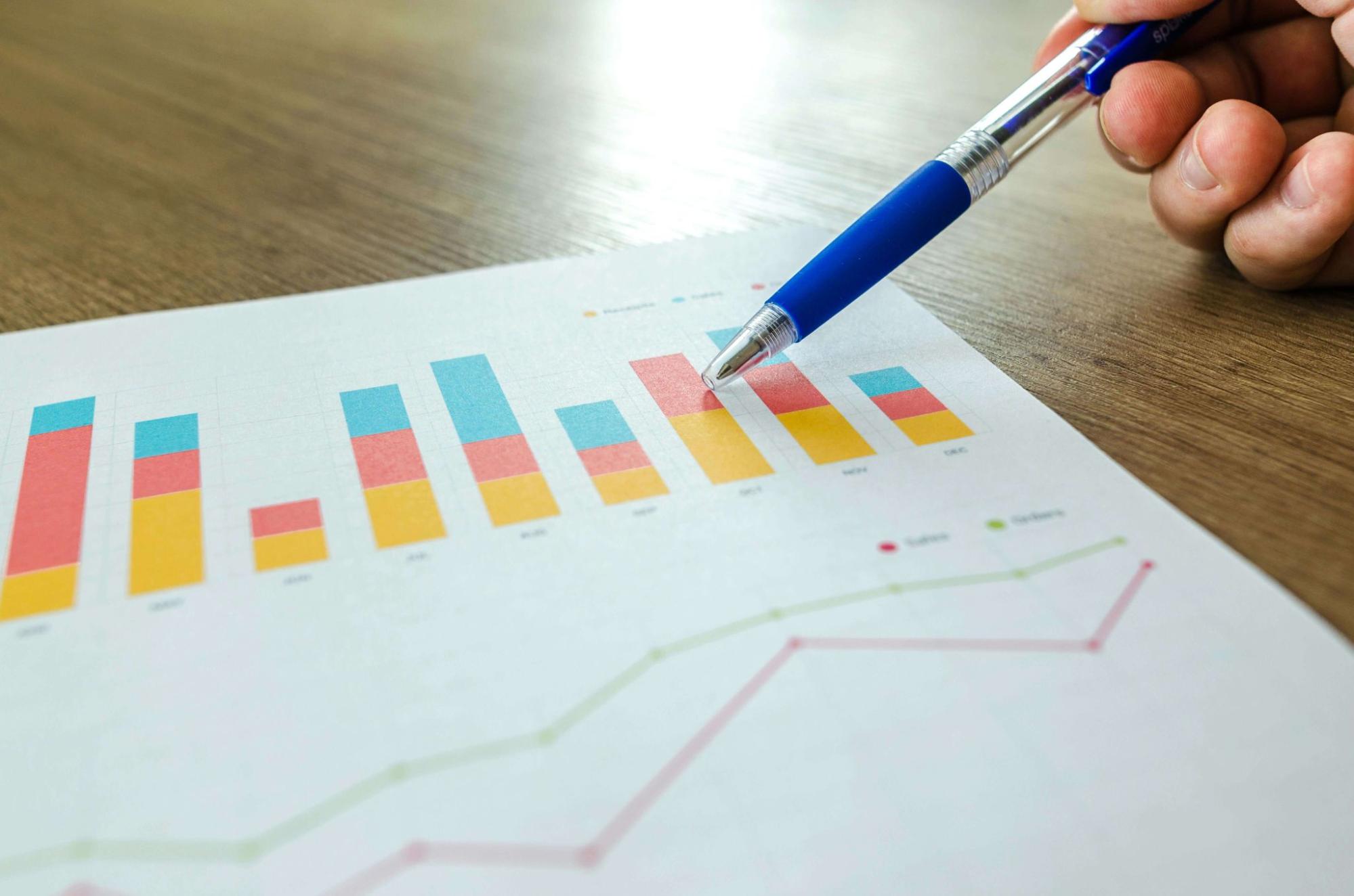 Person holding a pen and pointing at a graph